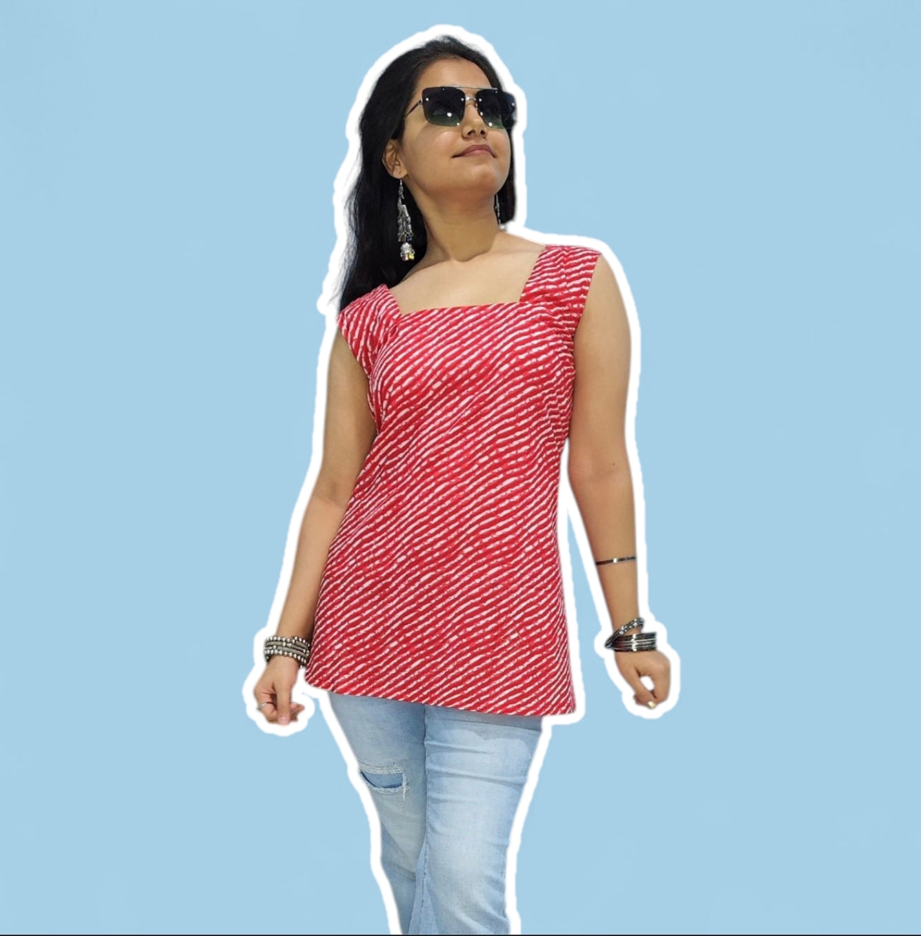 Woman wearing a red patterned top and light blue jeans against a light blue background