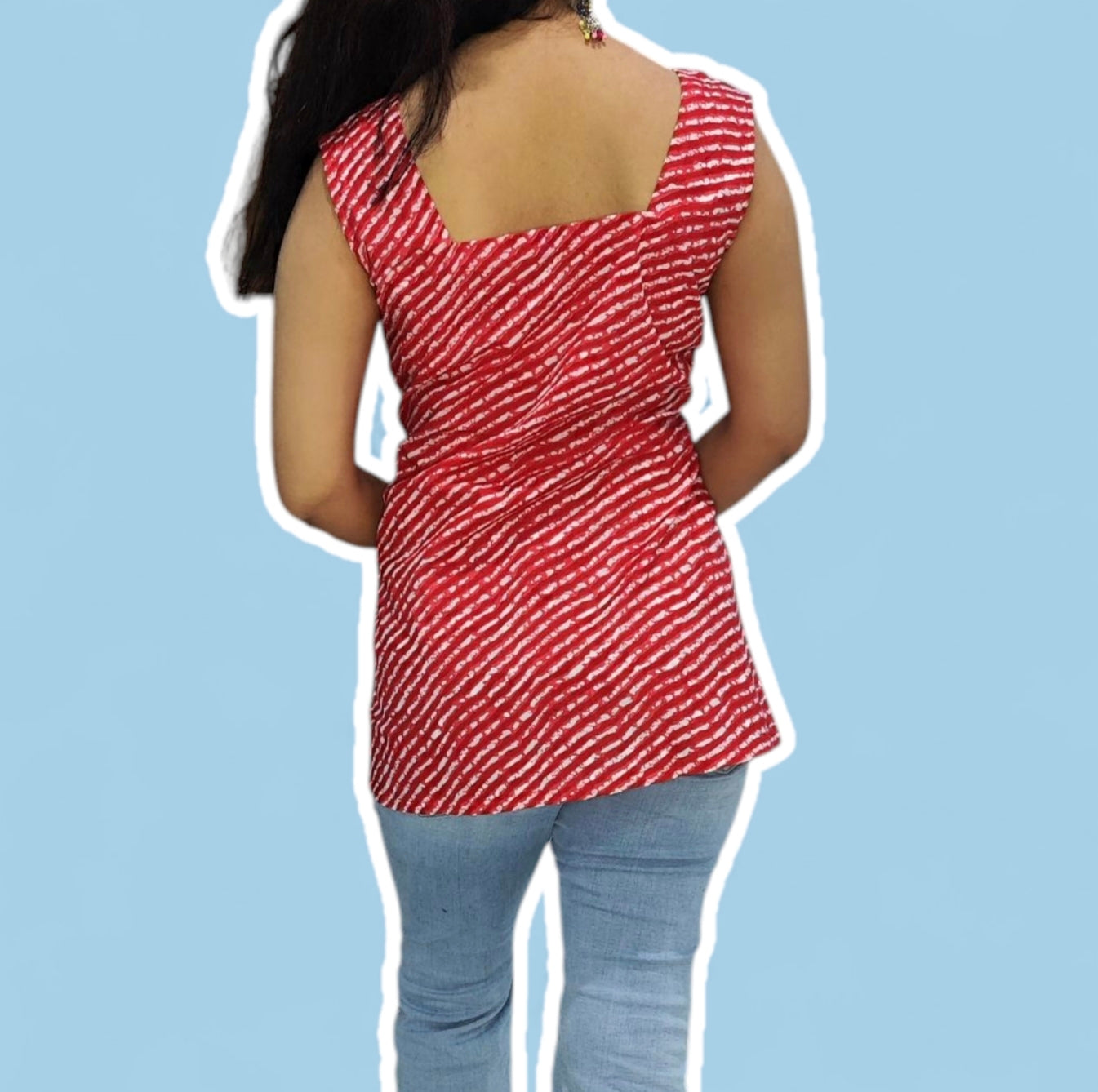 Person wearing a red patterned top and blue jeans on a light blue background