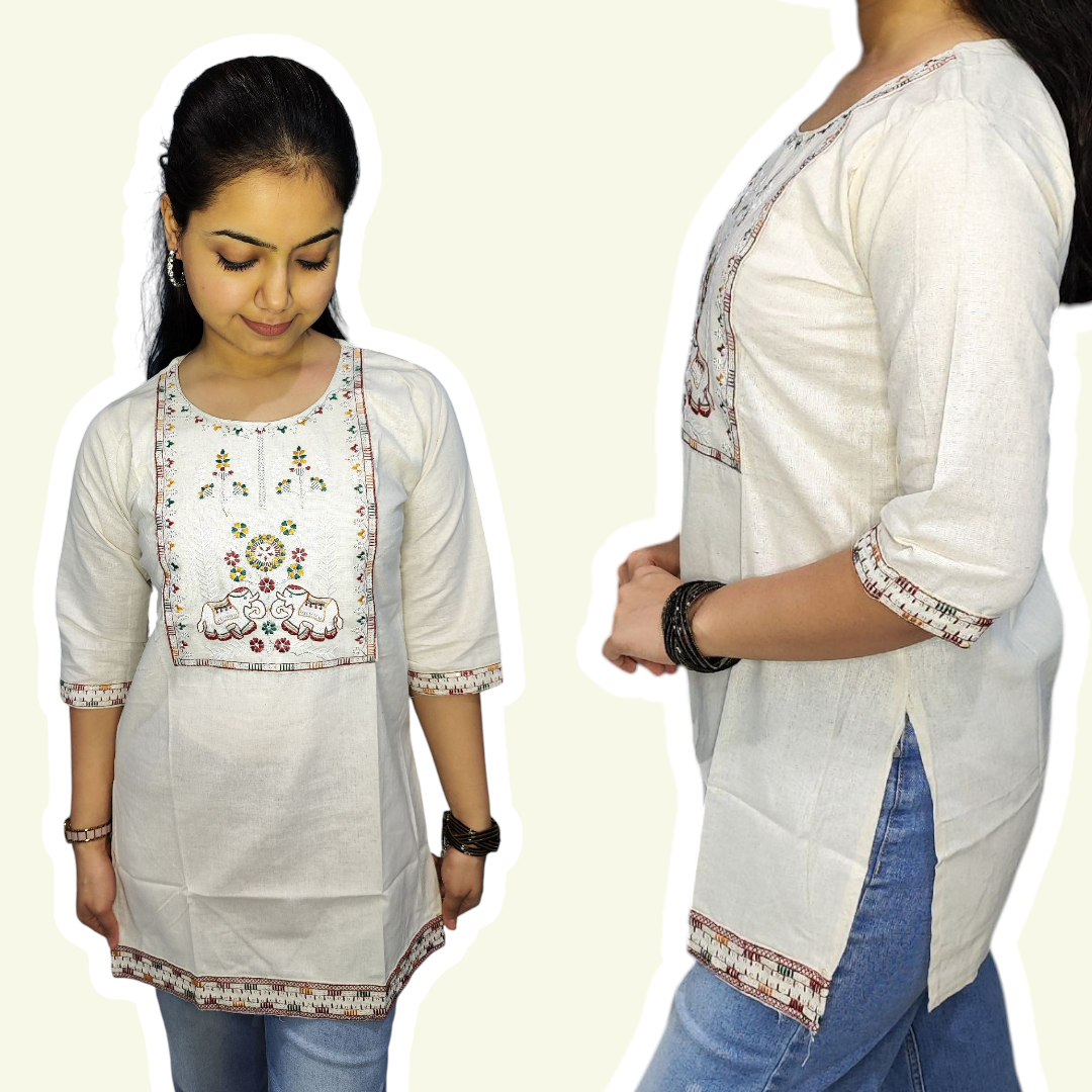 White embroidered top worn by a person on a plain background